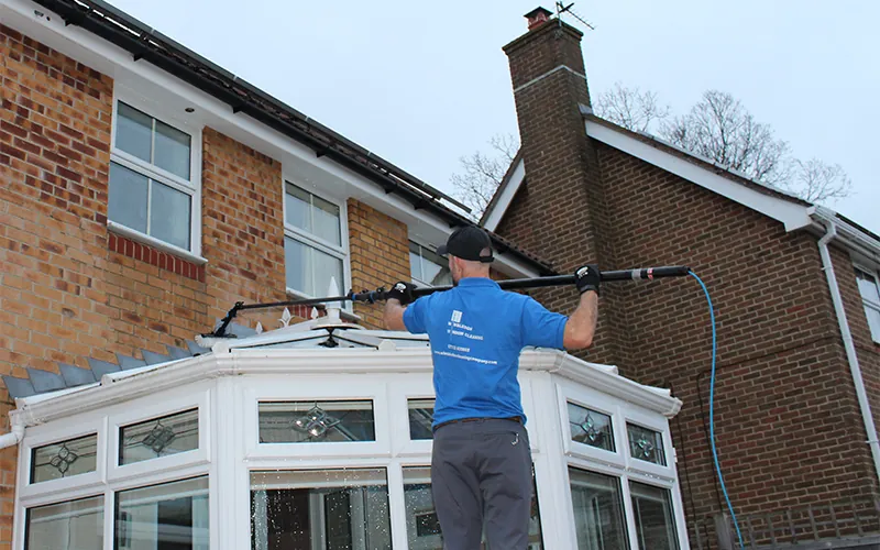 Technician cleaning a conservatory roof from the ground