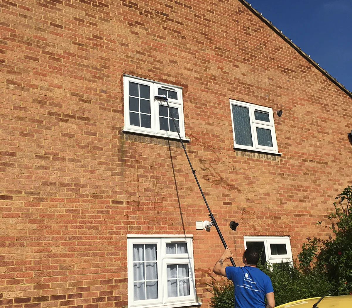 Wimbledon Cleaning Company technician cleaning first-floor windows with a pure water pole