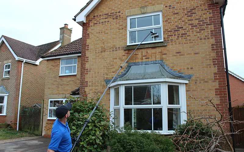 Technician cleaning bay windows with a pure water pole